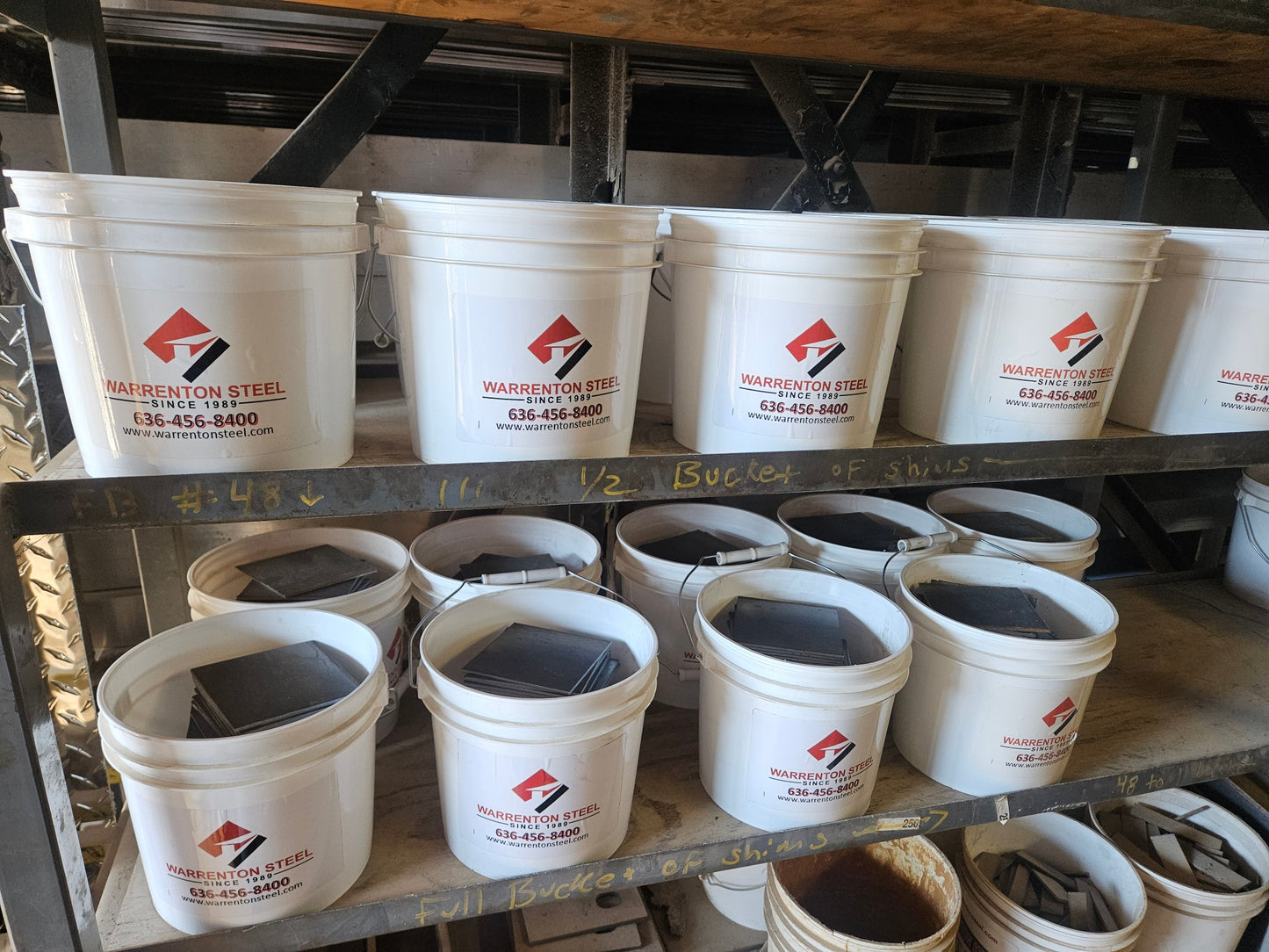 Several buckets full of steel shim plates on a shelf