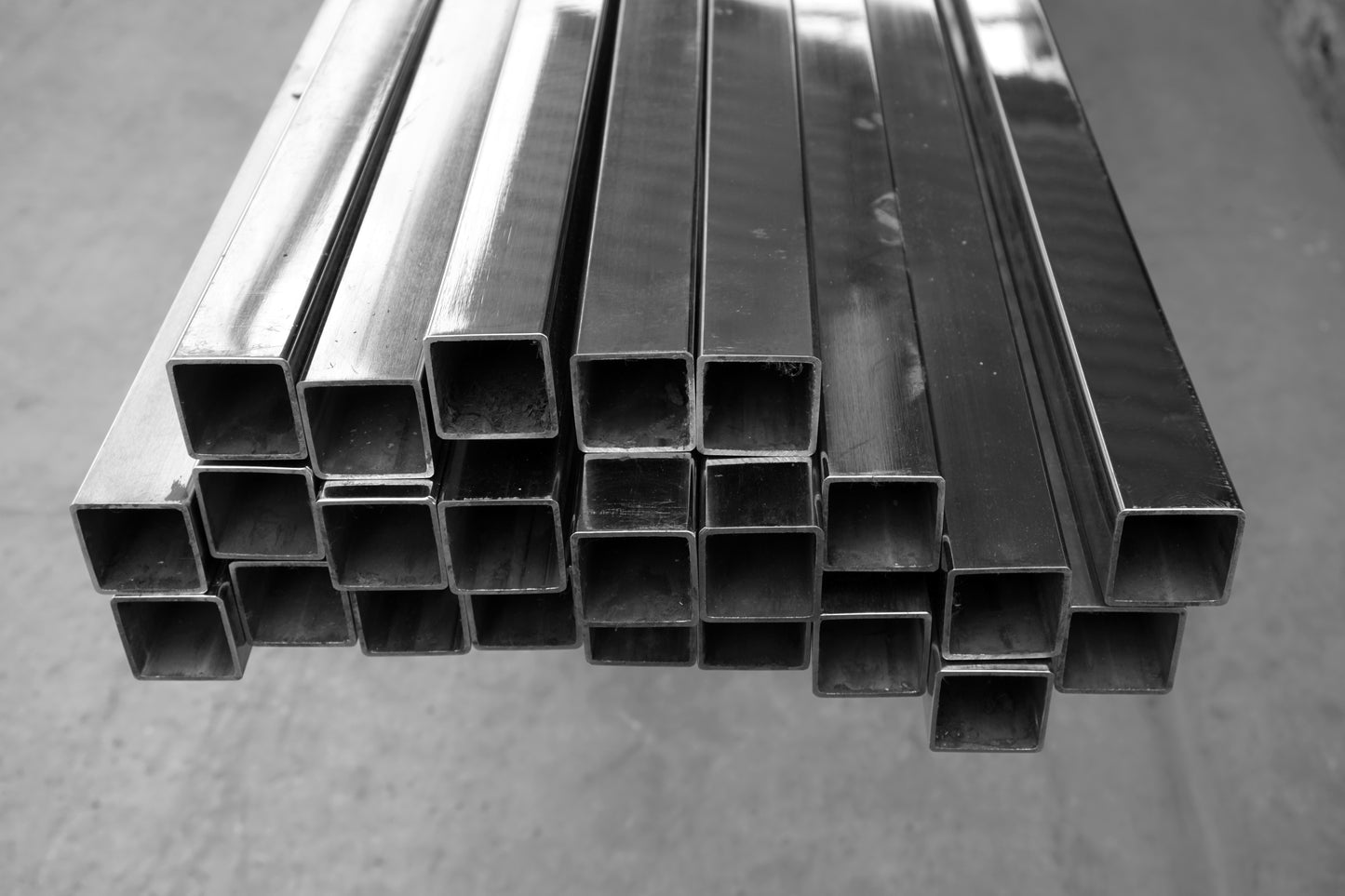 Stack of metal square tubes on a gray surface