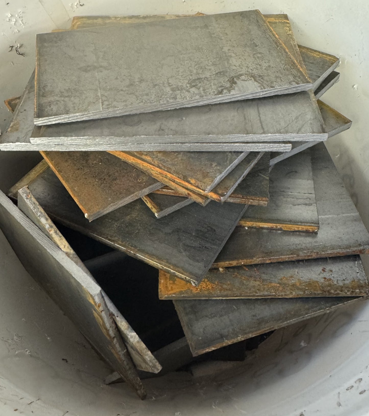 A pile of random lengths of flat bar plate steel welding practice coupons with varying lengths from 1 to 4 inches.