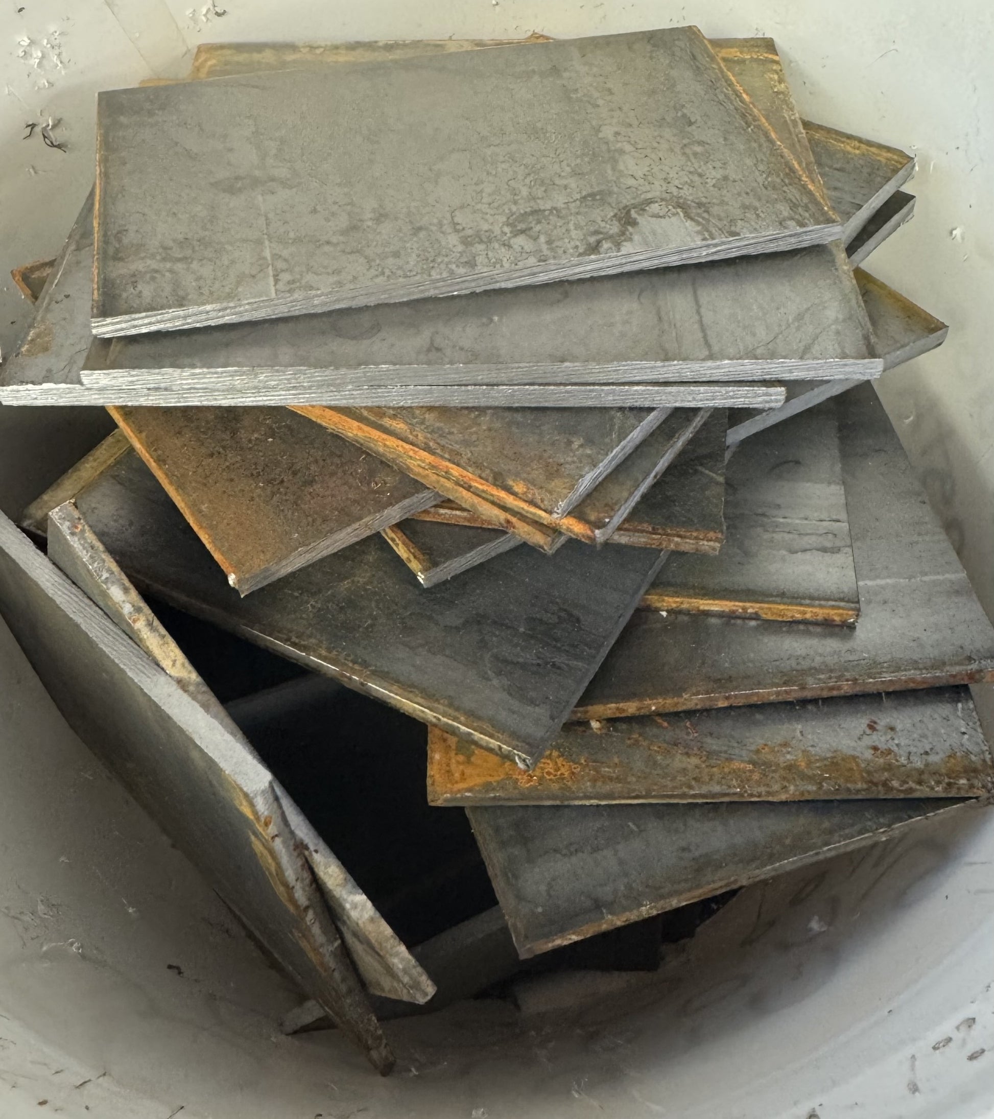 A pile of random lengths of flat bar plate steel welding practice coupons with varying lengths from 1 to 4 inches.